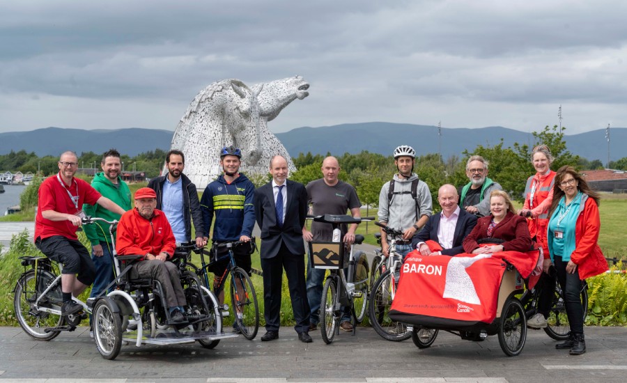 A large group of people with bikes in front of the Kelpies